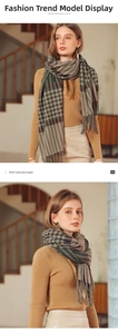 Detail of plaid cashmere-like scarf with green and brown tassels in soft winter light