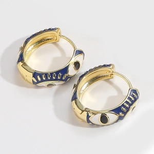 Detail of gold hoop earrings featuring blue and white enamel evil eye patterns on the side