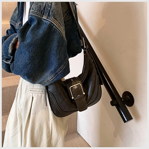 Detail der schwarzen Halbmond-Tasche mit übergroßer silberner Metallschnalle und breitem Gurt