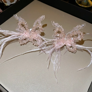 Detail of pink resin butterfly ear clips featuring crystal beads and soft feathers