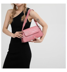 Detail of pink crocodile embossed shoulder bag with wide strap and flap closure