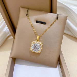 Macro view of gold plated square pendant with cubic zirconia inlay on jewelry box cushion