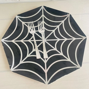 Close-up of silver plastic forks on a black hexagon plate with white spider web patterns