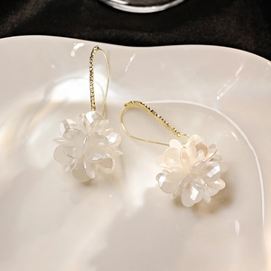 White shell flower earrings with tassel crystals on a white ceramic plate backdrop