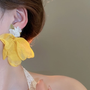 Detail of yellow mesh flower earrings with white beads on model for elegant vacation look