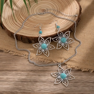 Detailed set of silver floral necklace and earrings with blue stone on rustic burlap