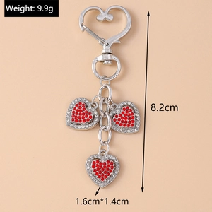 Close-up of silver heart keychain with red rhinestones and size dimensions in centimeters