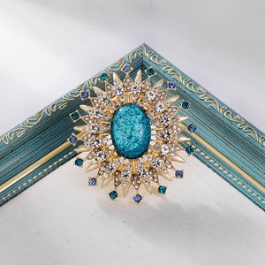 Vintage sunburst brooch with blue centerpiece stone and colorful crystal rhinestones
