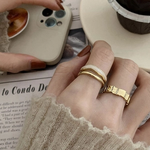 Golden double-layer mother-of-pearl ring and textured band on finger with coffee background
