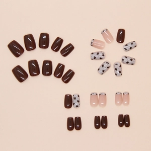 Detail van korte vierkante kunstnagels met koeprint en chocoladebruine afwerking