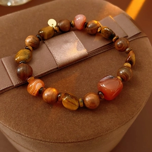 Détail d'un bracelet en perles d'œil de tigre et agate sur un coffret à bijoux en velours