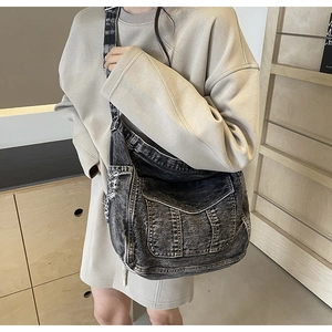 Détail du sac bandoulière en denim noir délavé avec coutures et poche avant