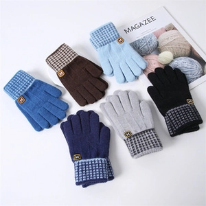 Detailed view of kids knitted winter gloves featuring plaid wrist cuffs and M letter tag