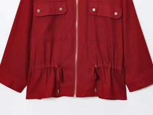 Detail of red linen-blend safari jacket featuring metal buttons and drawstring waist