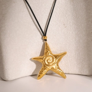 Detail view of 18k gold starfish pendant with spiral texture on a black cord necklace