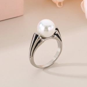 Dettaglio di una grande perla bianca rotonda su un anello in metallo argento sobrio