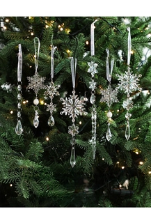 Clear acrylic snowflakes and icicles ornaments hanging on a warm lit Christmas tree