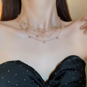 Details einer mehrlagigen Goldkette mit rosa Zirkonia an Hals und Schlüsselbein
