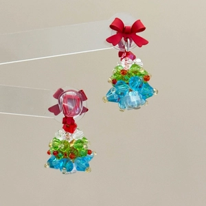 Macro detail of handmade beaded Christmas tree earrings with a red bow accent