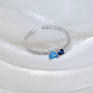 Detailed macro view of silver open ring with twisted texture and blue zircon stones