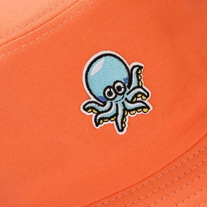 Détail de la broderie pieuvre mignonne sur le chapeau bob en coton orange vif