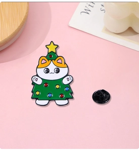 Detail of enamel Christmas cat pin wearing a green tree costume with colorful dots