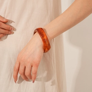 Close-up of amber resin bangle with marble texture worn on a female wrist