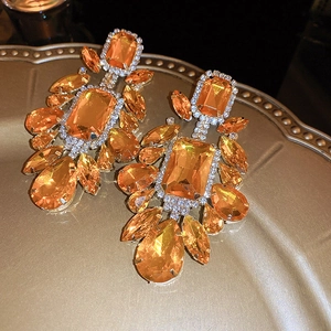 Macro shot of orange crystal droplet earrings with gold detailing and sparkle
