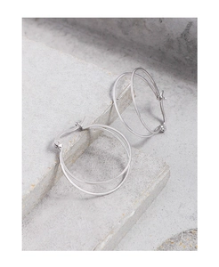 Macro detail of silver S925 double hoop earrings on a grey stone background