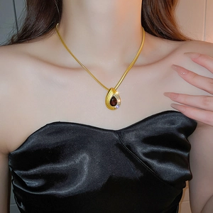 Close-up of golden teardrop pendant necklace with dark stone and sparkling diamonds