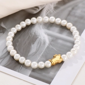 Detail of beaded pearl bracelet with golden rabbit charm on stylish background