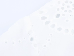 Close-up of white cotton blouse featuring intricate hollow embroidery and lace texture