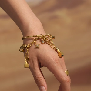 Goldenes Armband mit Stern- und Diamantanhängern am Handgelenk mit passendem Ring