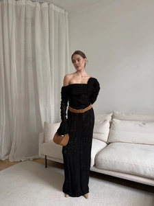 Detail of off-shoulder black knit dress with hollow-out pattern and chic brown waist belt