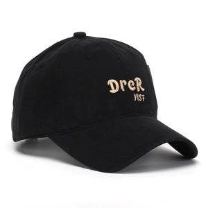 Close-up of golden embroidery on a black cotton baseball cap with detailed stitching