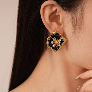 Gros plan de boucles d'oreilles fleurs vintage avec émail bleu et cristal brillant