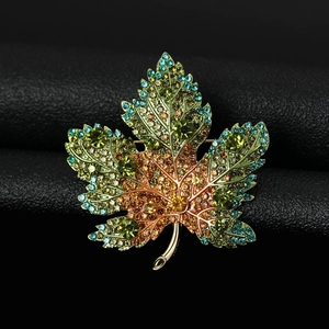 Macro shot of maple leaf brooch featuring multi-color rhinestones on gold metal base