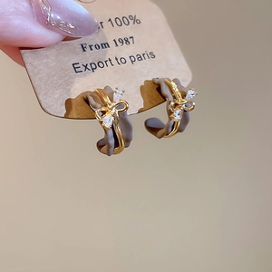 Detail of grey wavy hoop earrings with gold bow and sparkling crystal accent