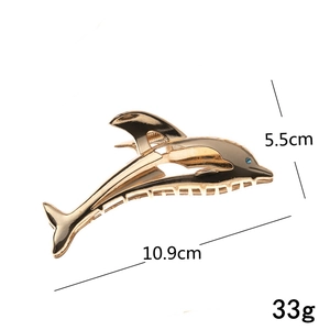 Detail view of gold dolphin hair claw with size 10.9cm and blue crystal eye