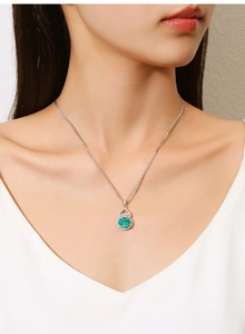 Gourd-shaped silver necklace featuring a green emerald pendant on a female model