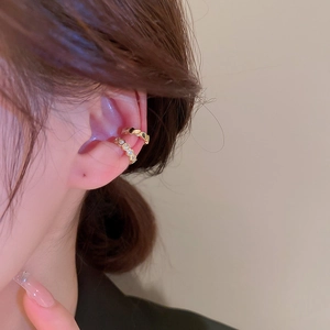 Detailed view of gold-plated honeycomb and rhinestone ear cuffs on a model's ear