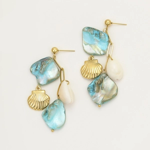 Makroaufnahme asymmetrischer goldener Ohrhänger mit natürlichen blau-weißen Muscheln