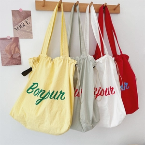 Hanging canvas tote bags with drawstring closure in four colors featuring Bonjour print