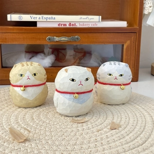 Detailed view of three carved wooden cat figurines with gold bells on a woven mat