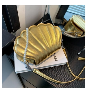 Detail der goldenen Muscheltasche mit Perlengriff und vertikalen Texturnähten