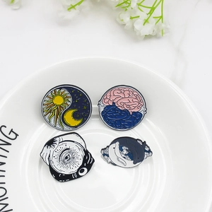 Set of four artistic enamel pins featuring sun moon and brain motifs on white plate