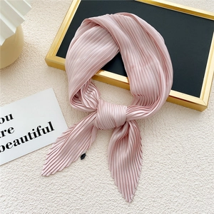 Pink pleated square silk scarf for women displayed on beige textured background