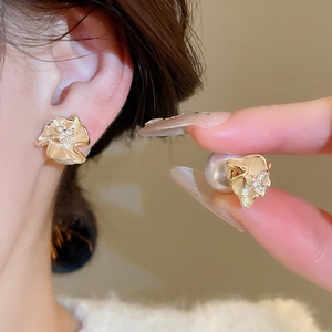 Detail of 18k gold plated floral stud earring with resin pearls and cubic zirconia