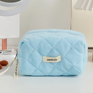 Detailed close-up of light blue quilted makeup bag with rhombic texture and cream label