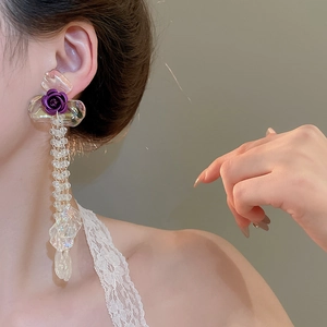 Close-up of elegant purple rose long tassel earrings with iridescent petals on a model
